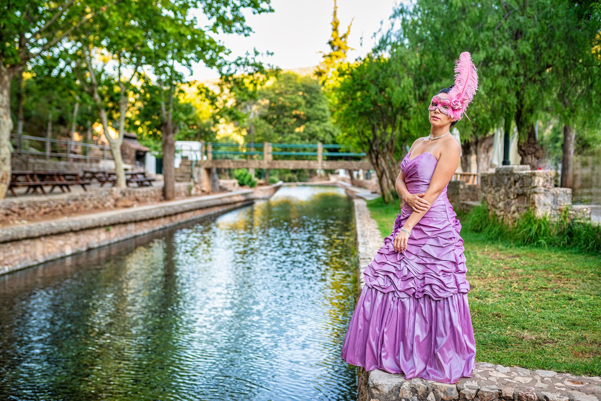 Venetian-Style Masked Woman in a Vibrant Gown by a Canal in Alte, Portugal